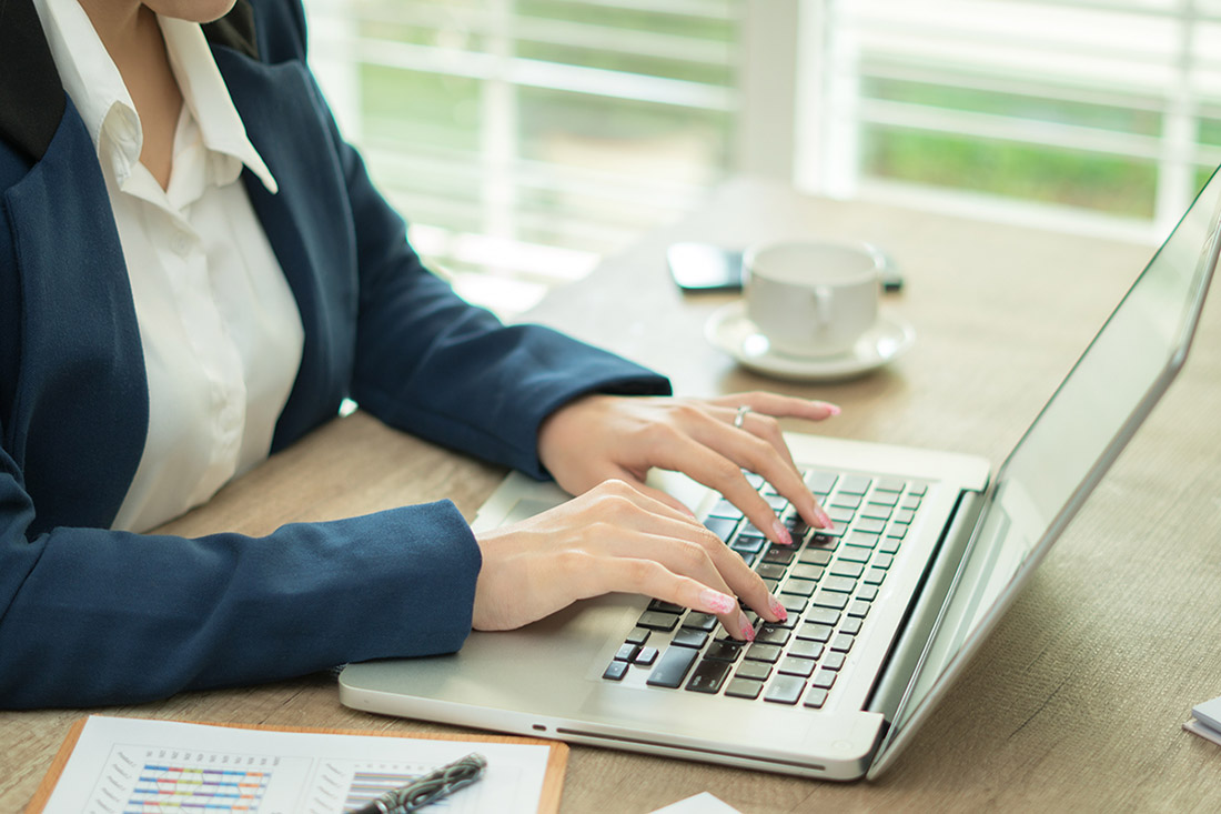 Woman working at home office hand on keyboard close up Femme avec un ordinateur portable